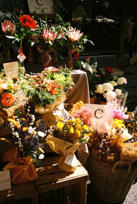 A display of freshly arranged floral bouquets and individual flower stems set on a wooden table at a flower shop near Clarendon Road Watford. The arrangements include vibrant blooms such as red roses,